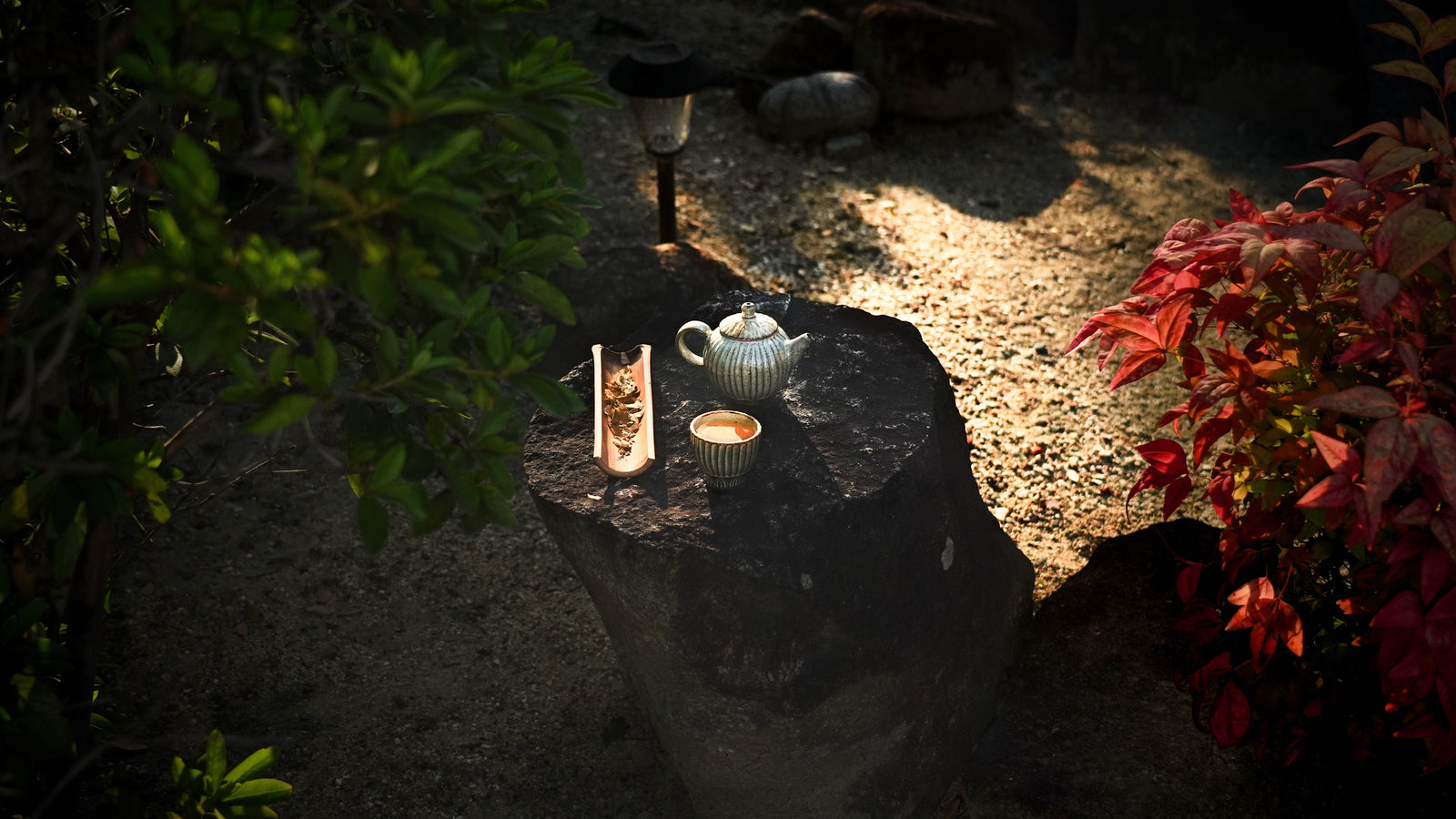 A Korean tea set on a garden stone at dusk